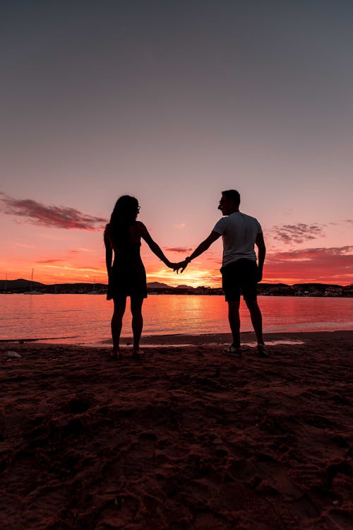 Couple Holding Hands on Shore at Sunset