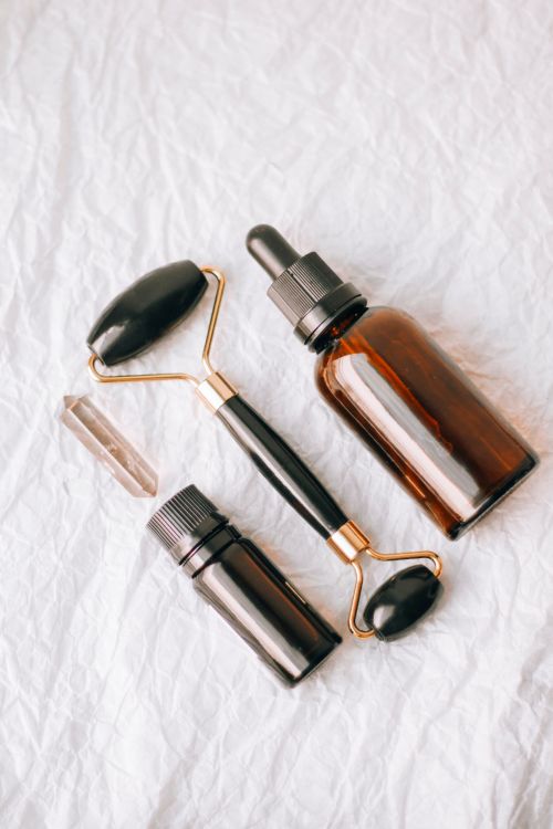 Free Flat lay of essential oil bottles and face roller on a textured white background. Stock Photo