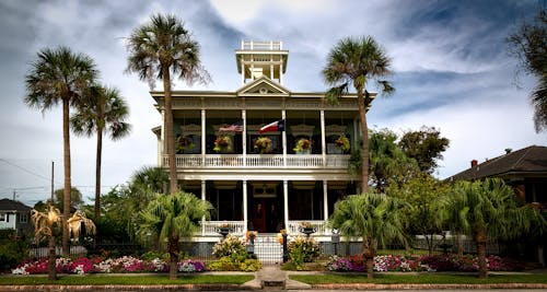 White Painted Structure With Green Palm Trees in the Front