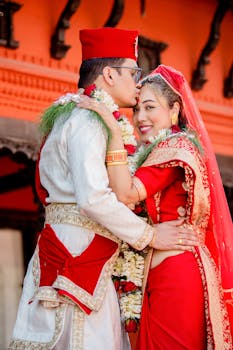 A couple in traditional attire embracing during their wedding ceremony outdoors.