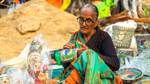 An old woman sitting on the ground with a basket