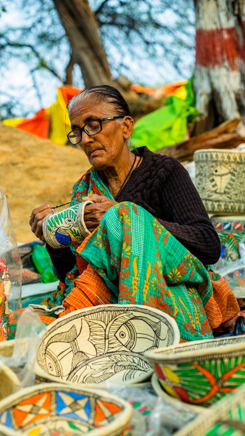 A woman is sitting on the ground with bowls