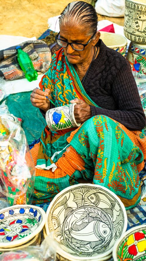 Free An elderly woman skillfully creating traditional handicrafts at a local Indian market. Stock Photo