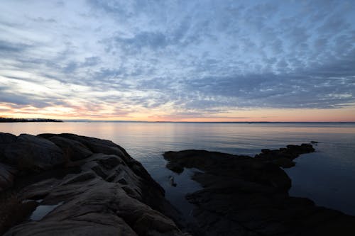 Silhouetted Rocky Shore and a Body of Water at Sunset