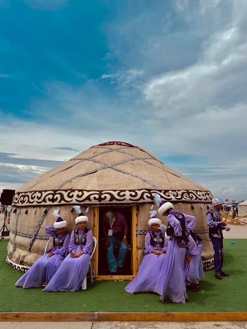 People in purple clothing standing around a yurt