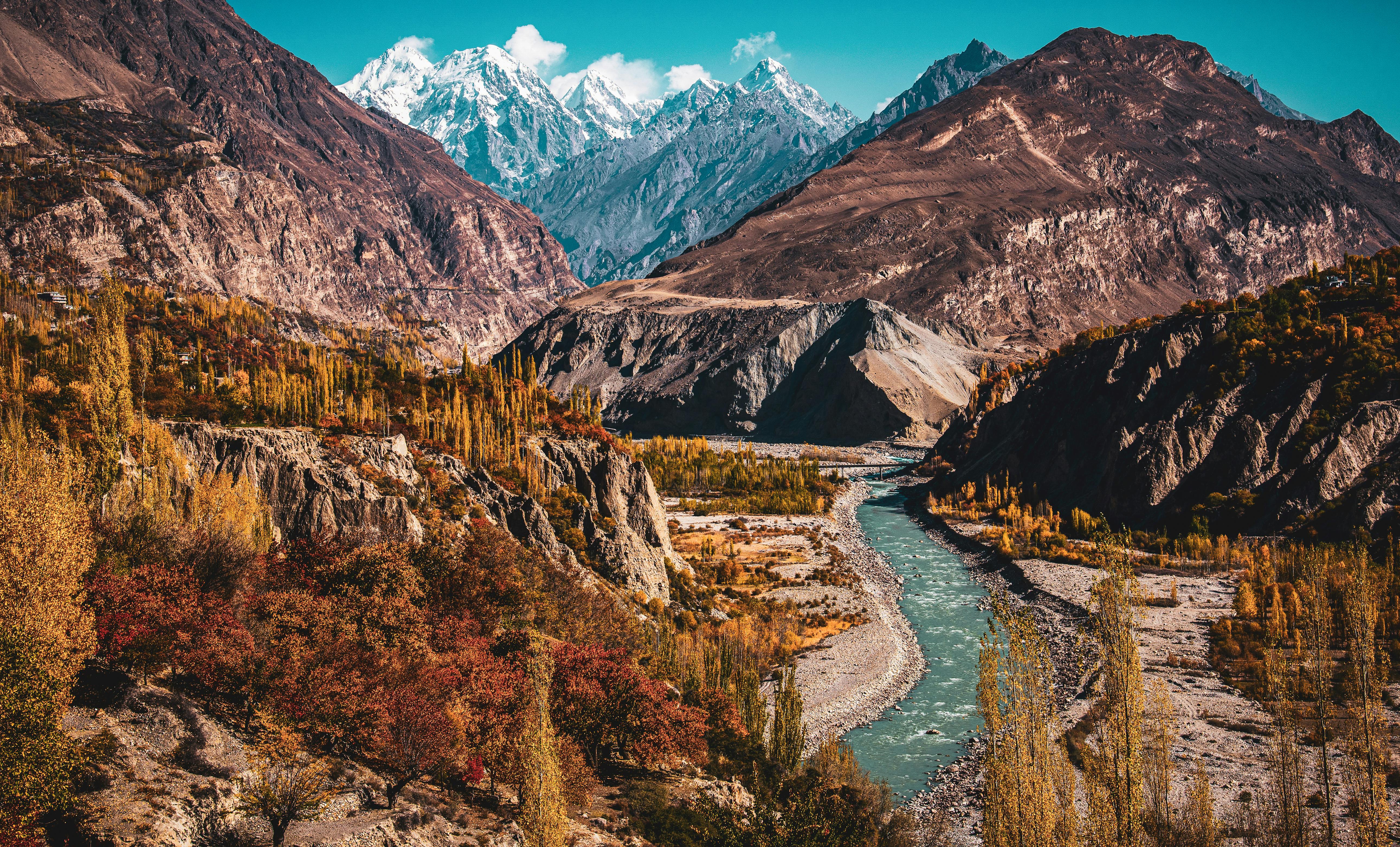 Breathtaking aerial view of a winding river in a mountain valley with vibrant autumn foliage.