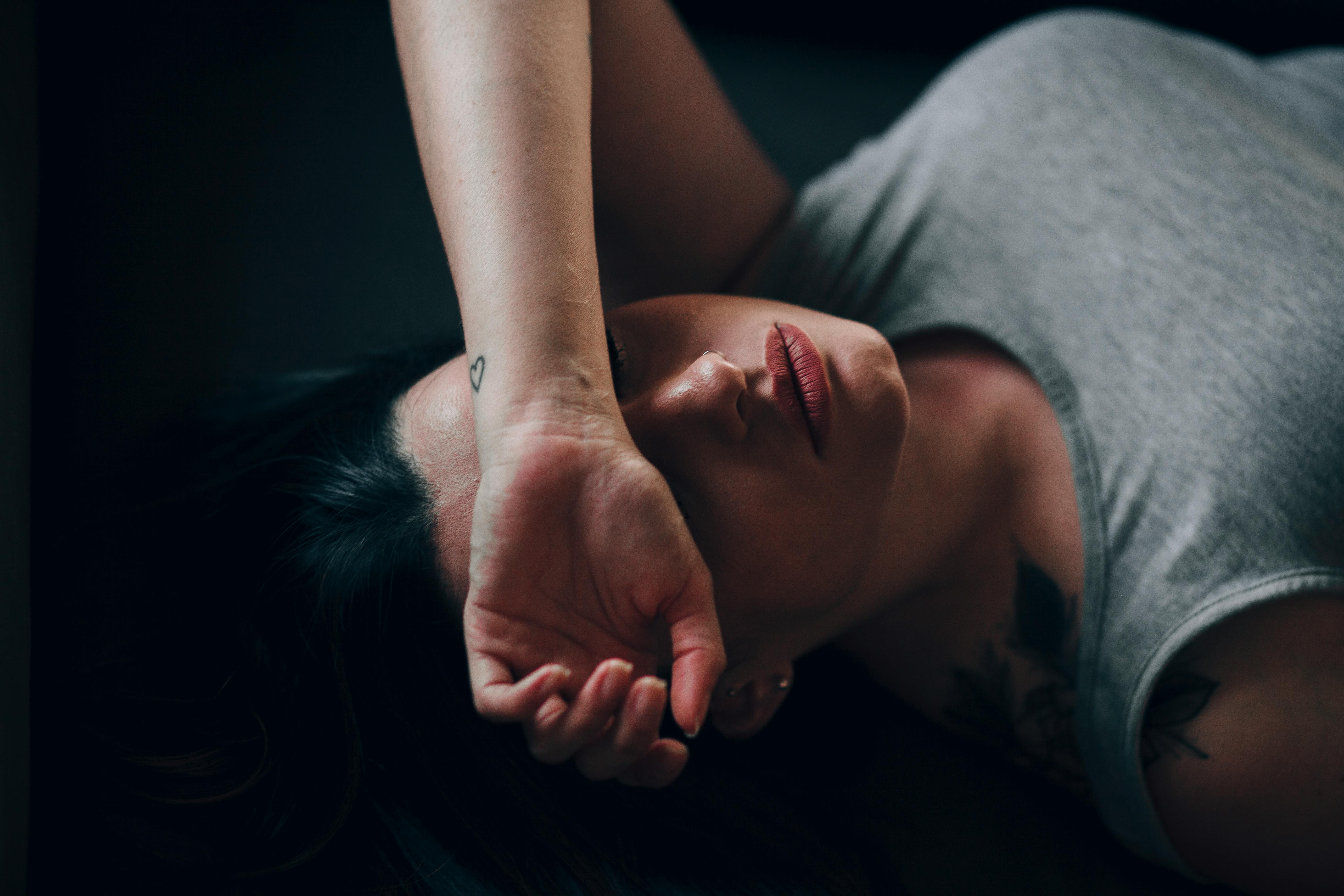 Mulher acordando sem energia, sentada na beira da cama com expressão de exaustão, luz de manhã cedo