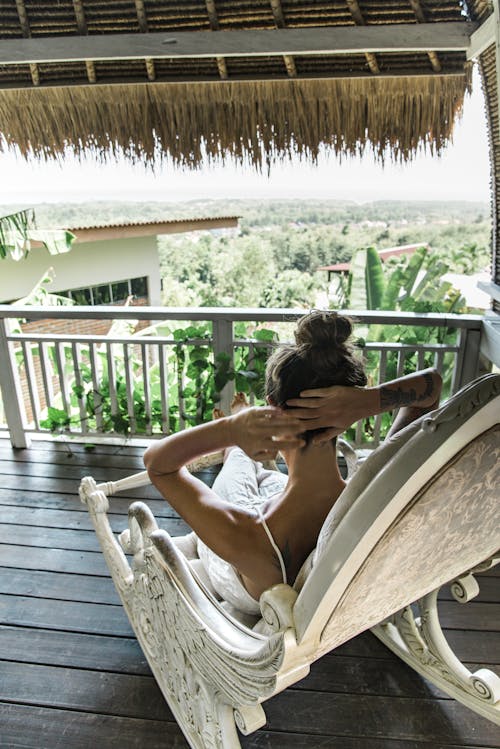 Woman Sitting in an Armchair on a Balcony in a Tropical Resort 