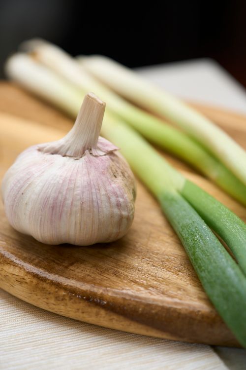 Free Close-up of fresh garlic and leeks on a wooden tray, perfect for cooking inspiration. Stock Photo