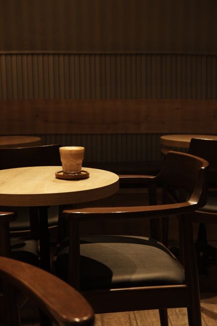 Warm, dimly lit cafe with a cozy atmosphere featuring empty wooden chairs and tables.