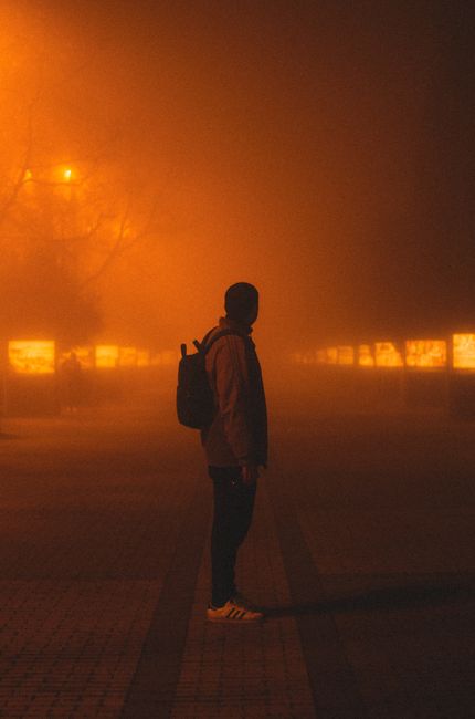 A silhouette of a man in a foggy, backlit city street, evoking mystery and intrigue.
