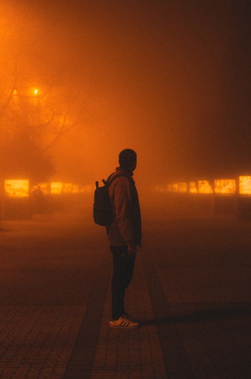 Free A silhouette of a man in a foggy, backlit city street, evoking mystery and intrigue. Stock Photo