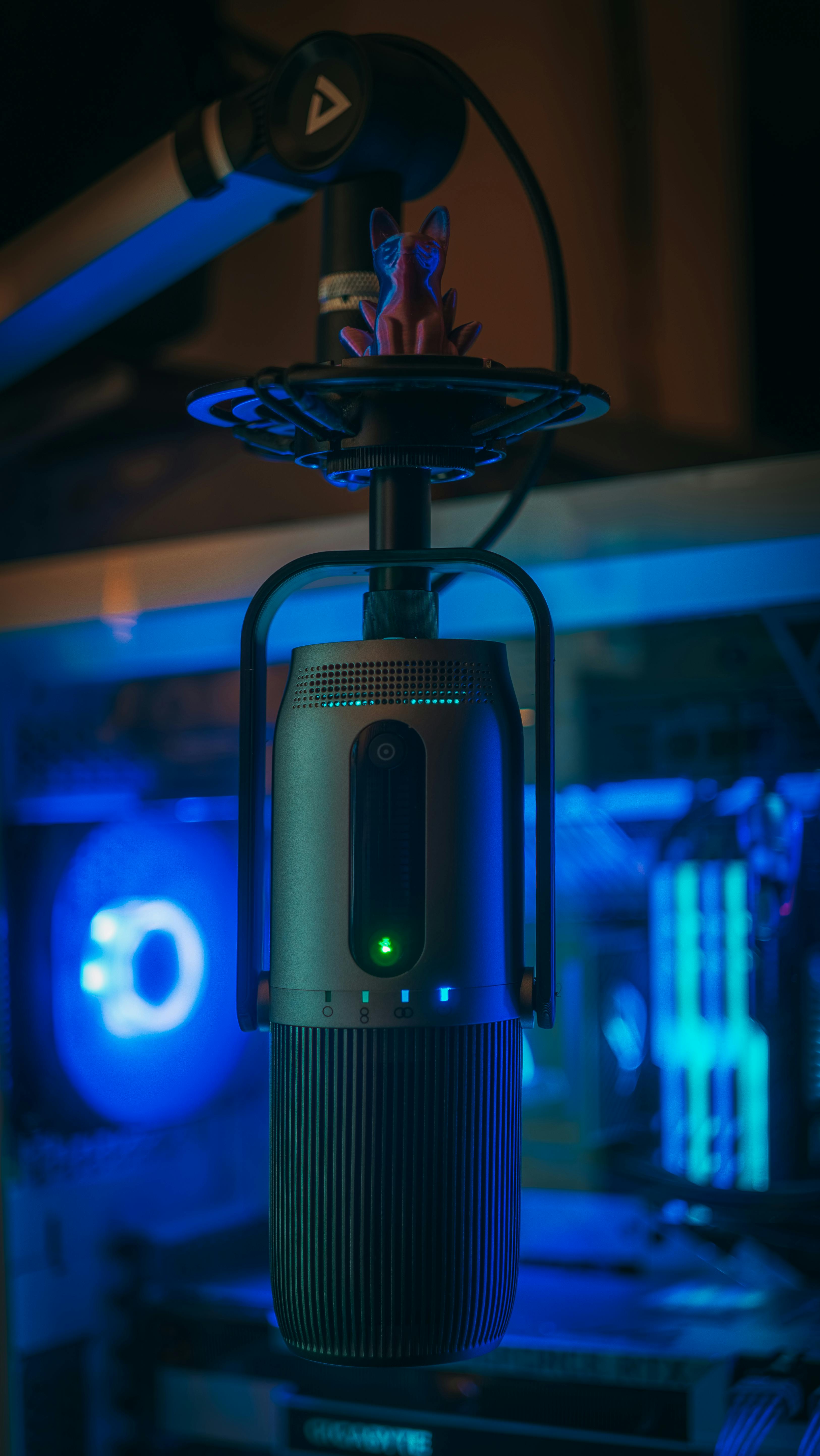 A sleek studio microphone illuminated by blue light, highlighting a professional technology setup for sound recording.