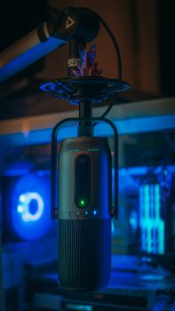 A sleek studio microphone illuminated by blue light, highlighting a professional technology setup for sound recording.