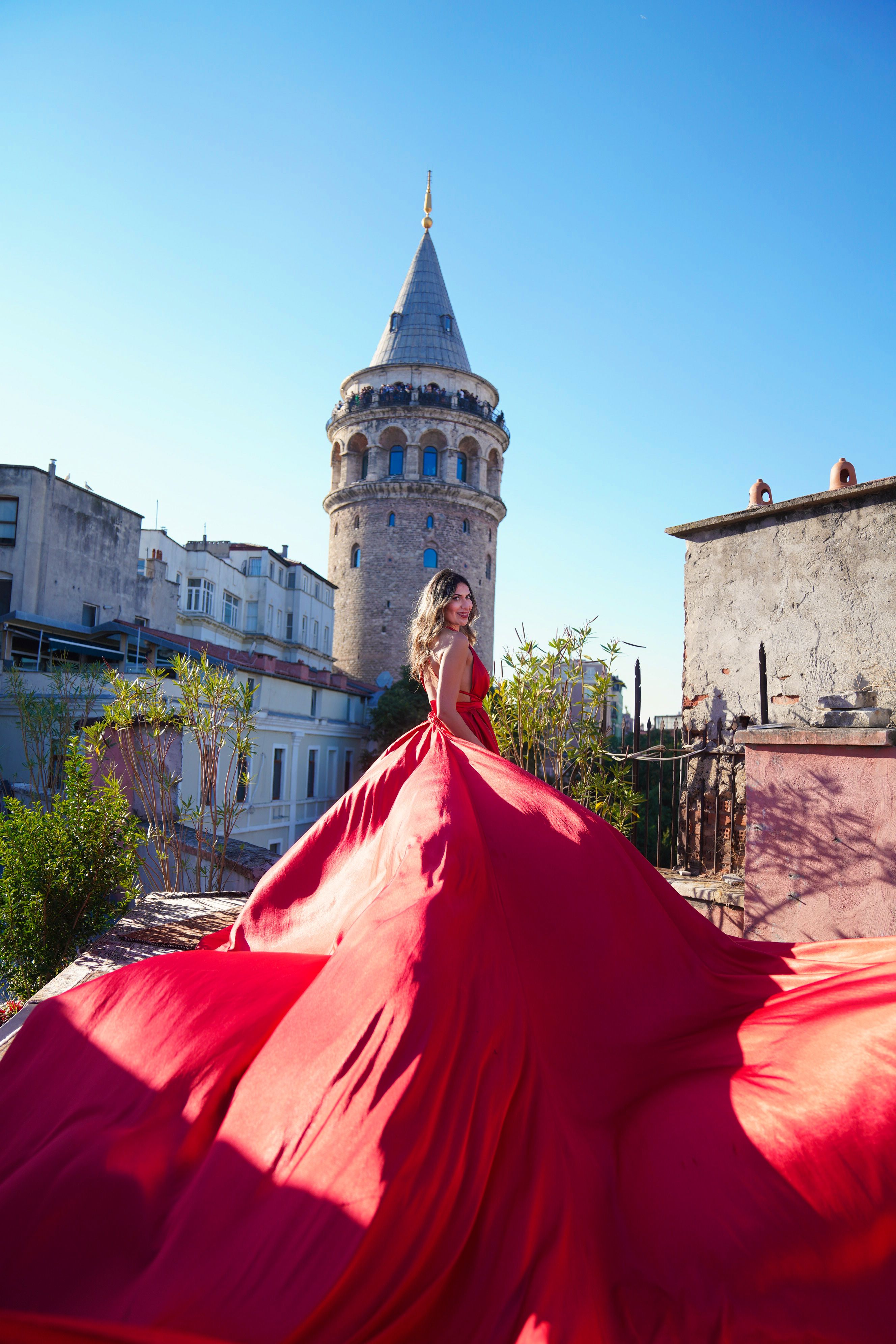 Woman in a stunning red dress posed near the iconic Galata Tower in Istanbul, Turkey.