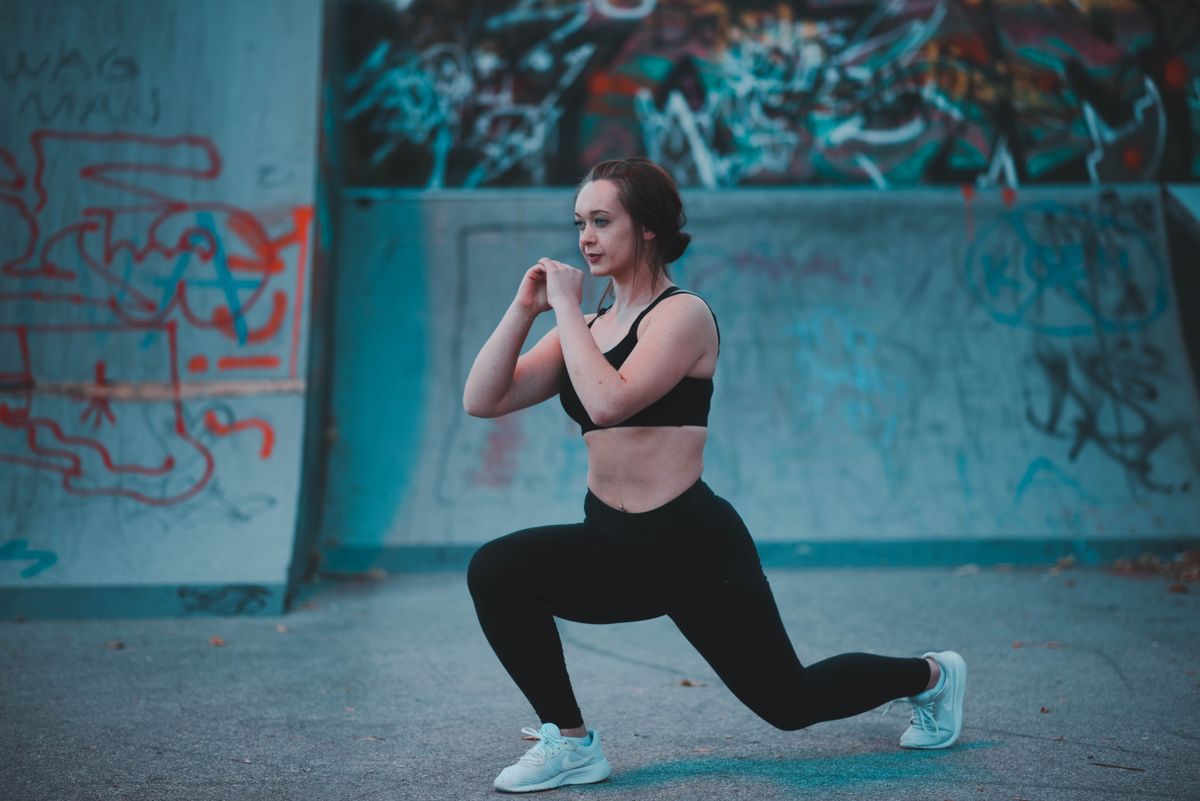 Woman performing lunges in athletic wear as part of a warm-up routine