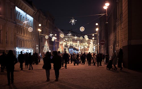 People Walking in City Decorated at Night in Winter