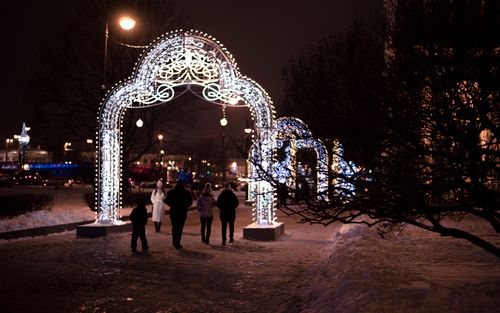 Free People walking under illuminated arches during a snowy winter night. Stock Photo