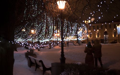 Free A snowy park at night with enchanting lights and people enjoying a winter walk. Stock Photo