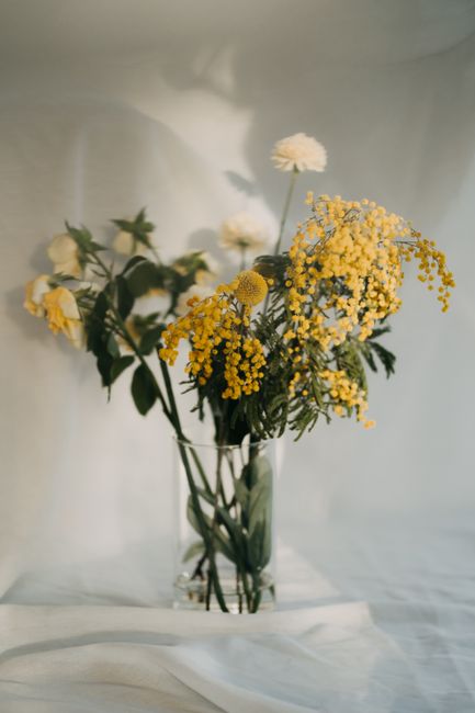 Beautiful bouquet of yellow and white flowers in a glass vase photographed in soft light.
