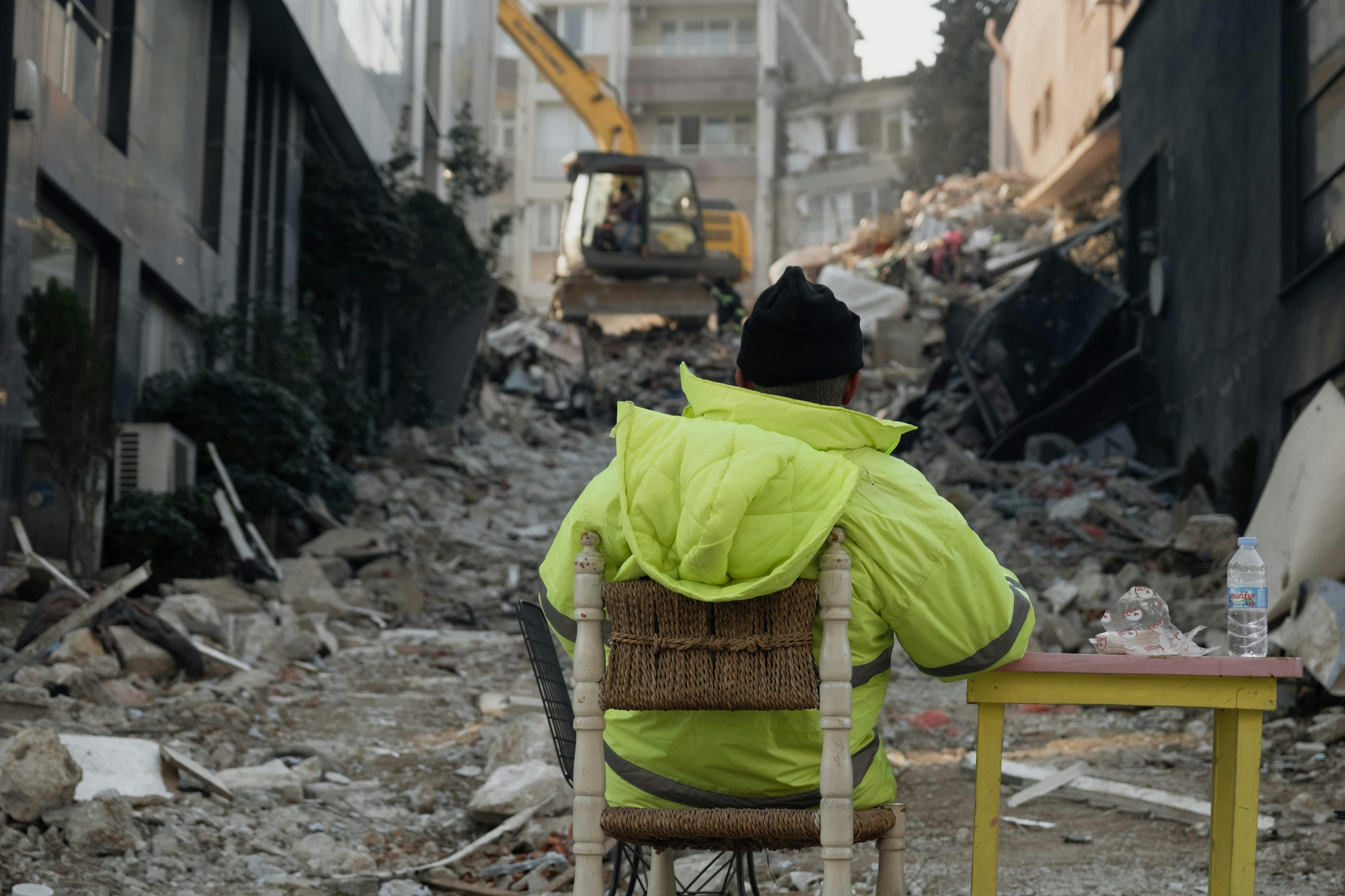 A construction worker sitting amidst debris after an earthquake in Antakya, Türkiye.