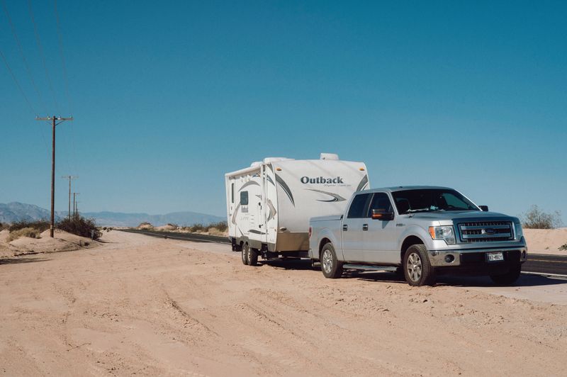 A pickup towing a trailer on a desert highway, photo by Alfo Medeiros on Pexels