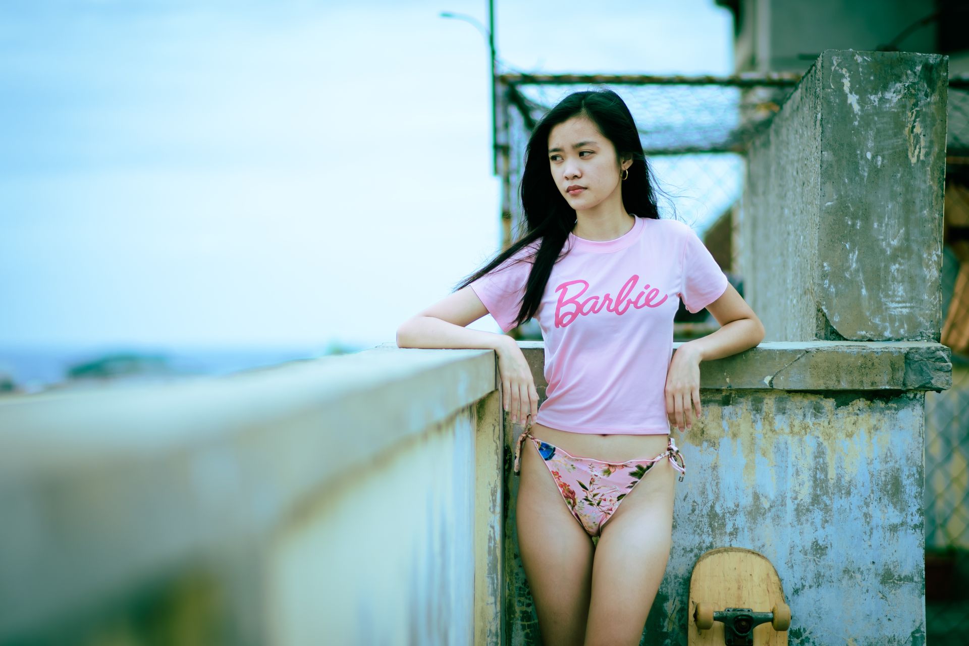 Young woman posing outdoors in a Barbie t-shirt and bikini, exuding confidence.