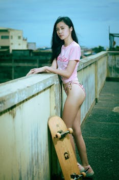 Stylish young woman posing on a rooftop with a skateboard, embodying summer leisure and fashion vibes.
