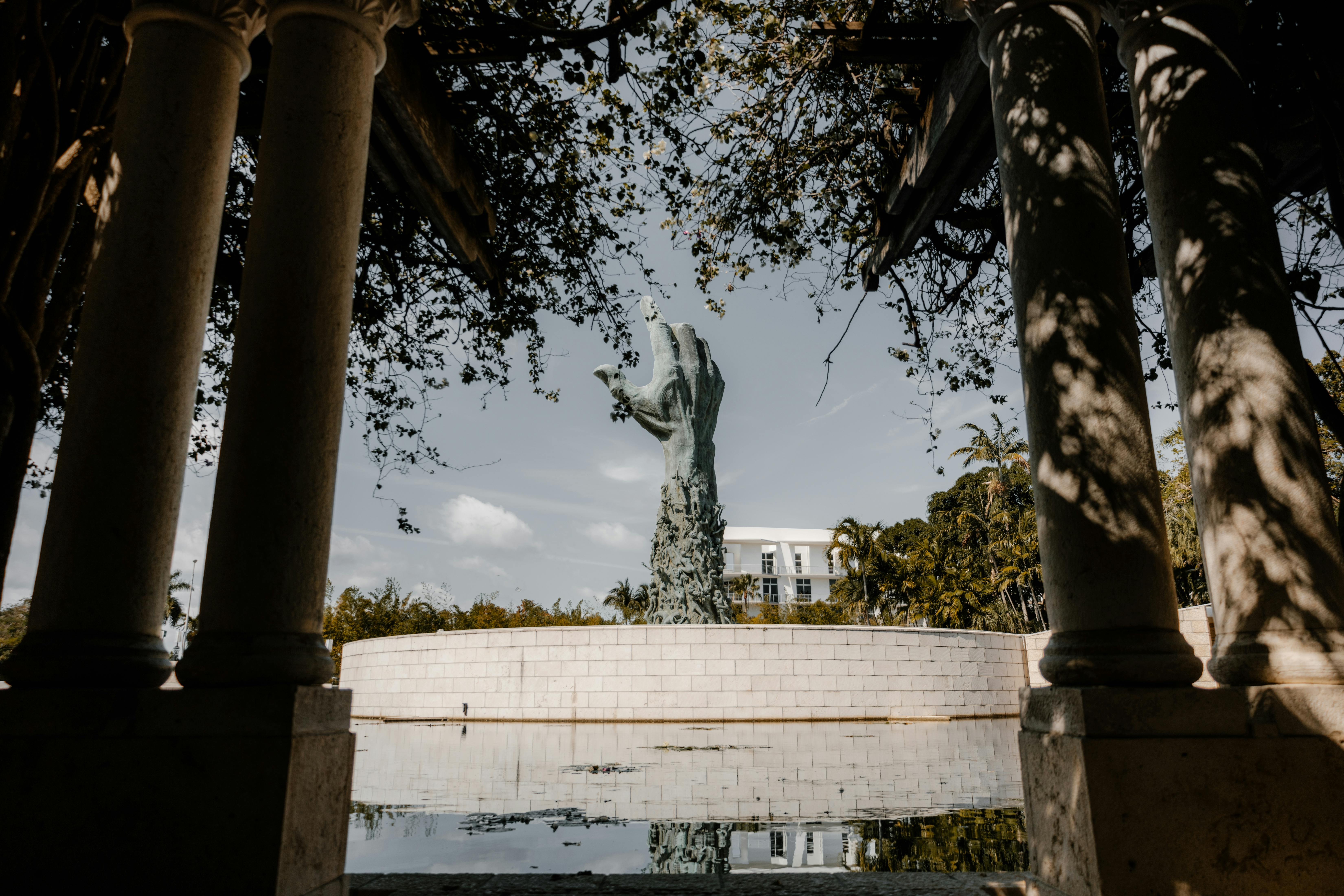 A dramatic view of the Holocaust Memorial statue framed by stone columns in Miami, Florida.