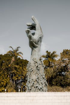 Vertical shot of a Holocaust memorial statue in Miami park surrounded by lush greenery.