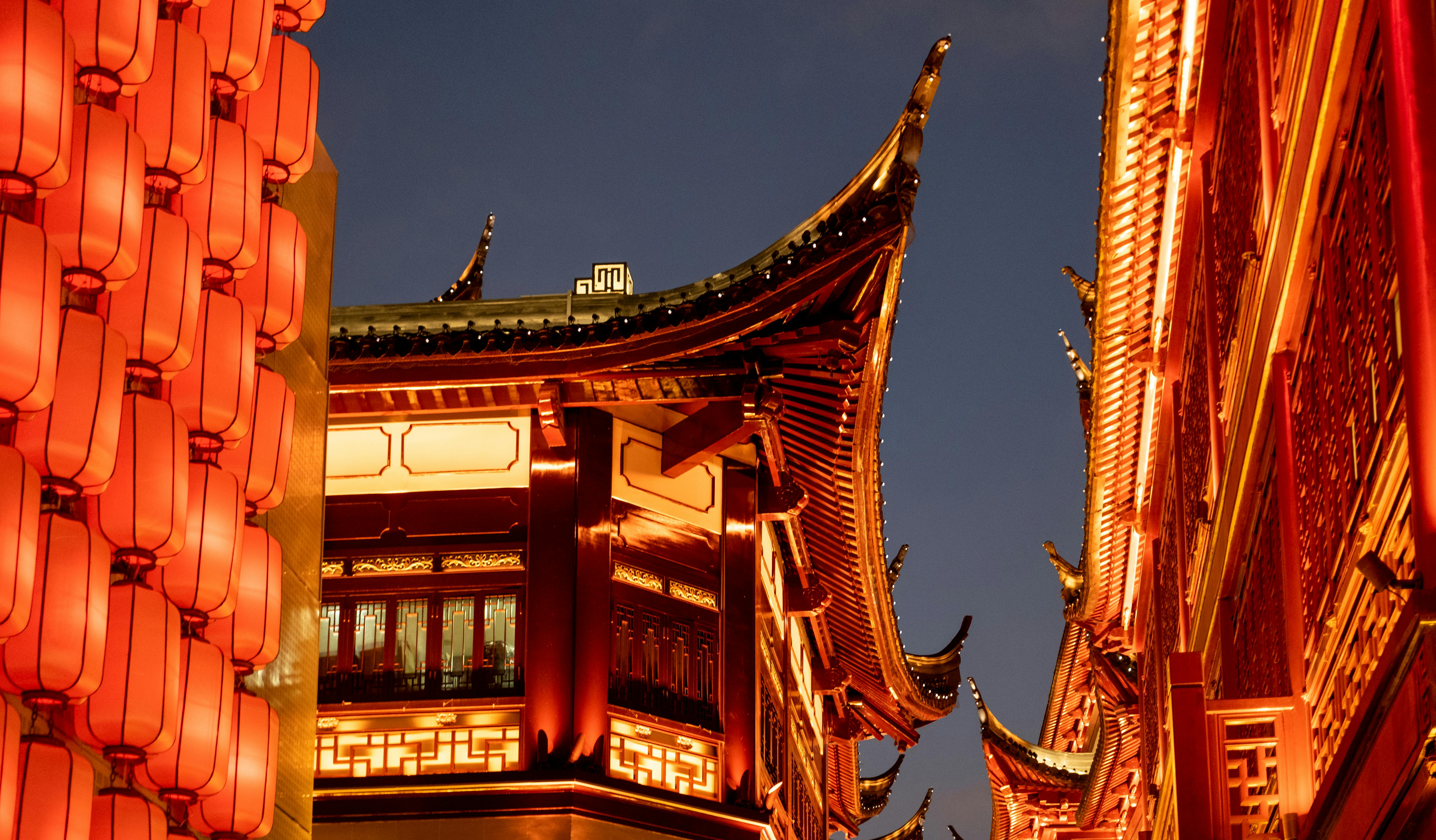Nighttime view of illuminated traditional Chinese architecture featuring red lanterns in Shanghai.