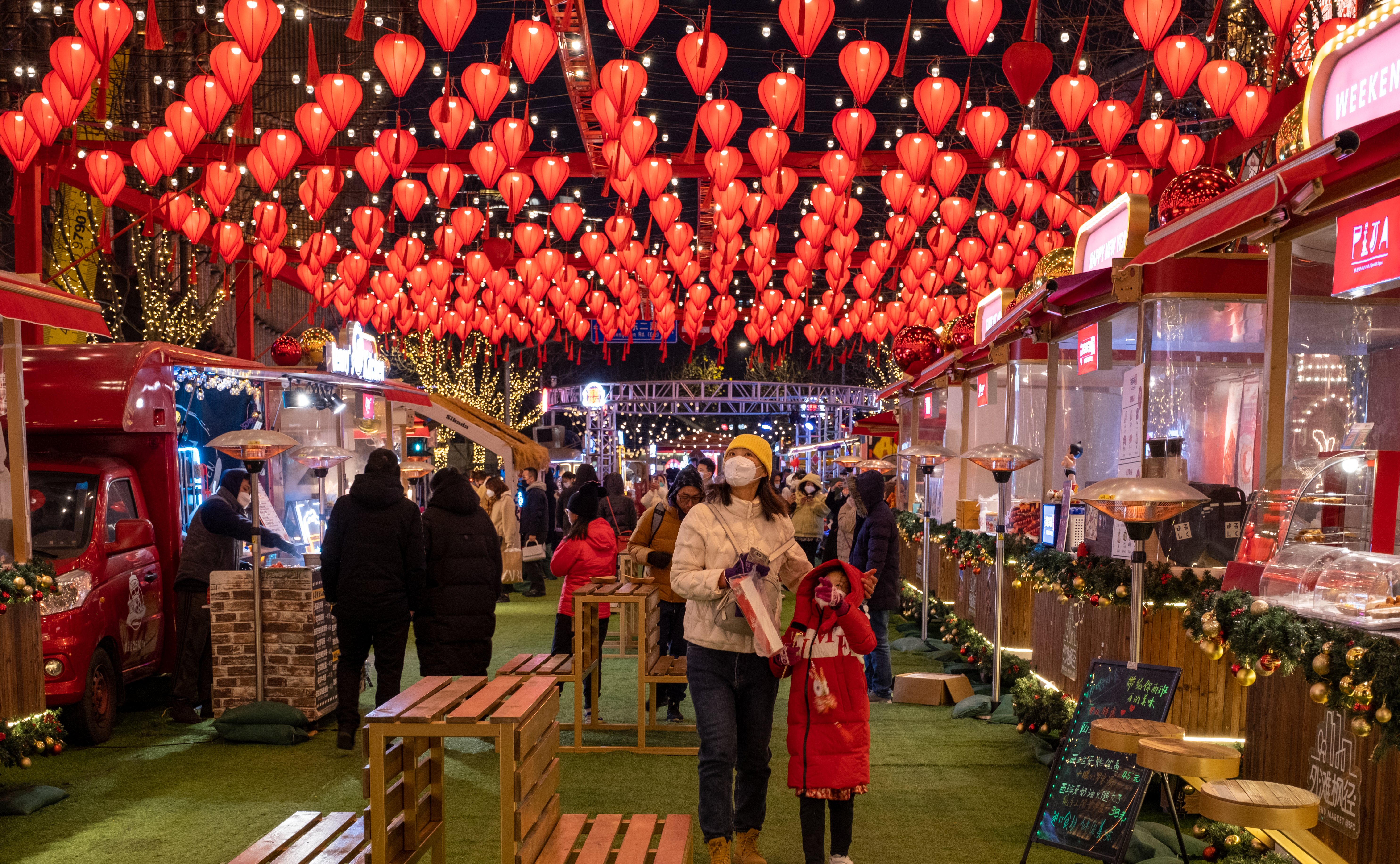 Colorful night scene of a bustling market with red lanterns and people wearing masks.