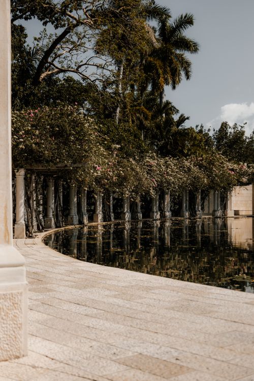 Free Peaceful scene of a curved pathway beside a tranquil pond surrounded by lush greenery in Miami. Stock Photo