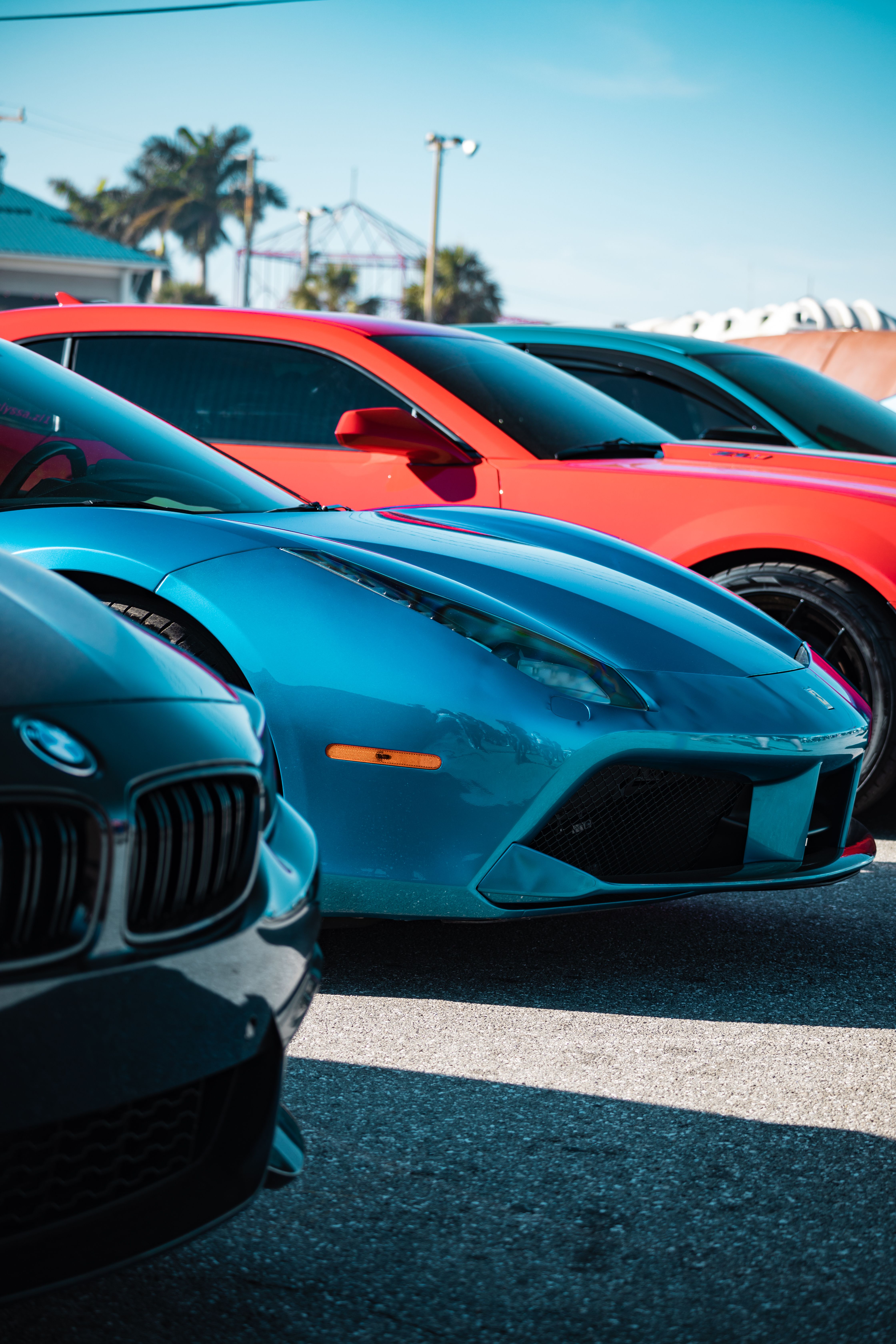 A vibrant lineup of luxury sports cars in various colors parked outdoors in daylight.