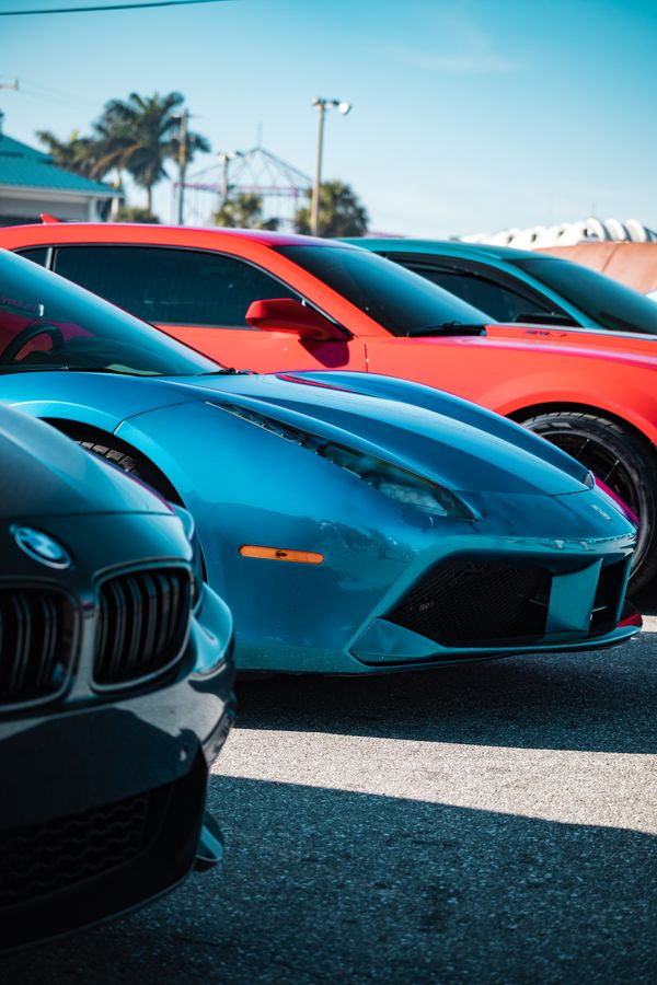 Uma vibrante coleção de carros esportivos de luxo em várias cores estacionados ao ar livre durante o dia.