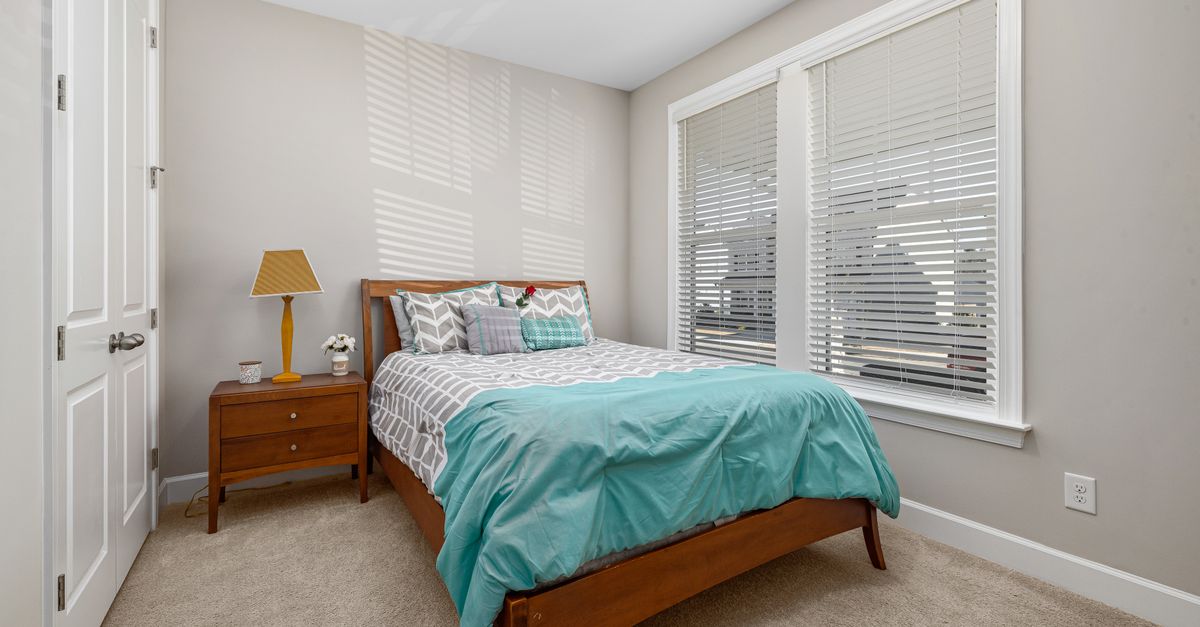 A cozy bedroom interior featuring a bed with teal bedding and wooden furniture.