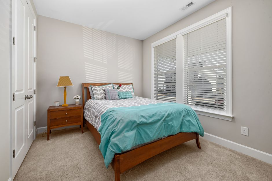 A cozy bedroom interior featuring a bed with teal bedding and wooden furniture.