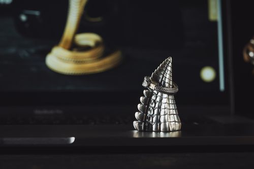 Free Close-up of a silver dragon-inspired ring displayed elegantly on a textured stand with a dark backdrop. Stock Photo
