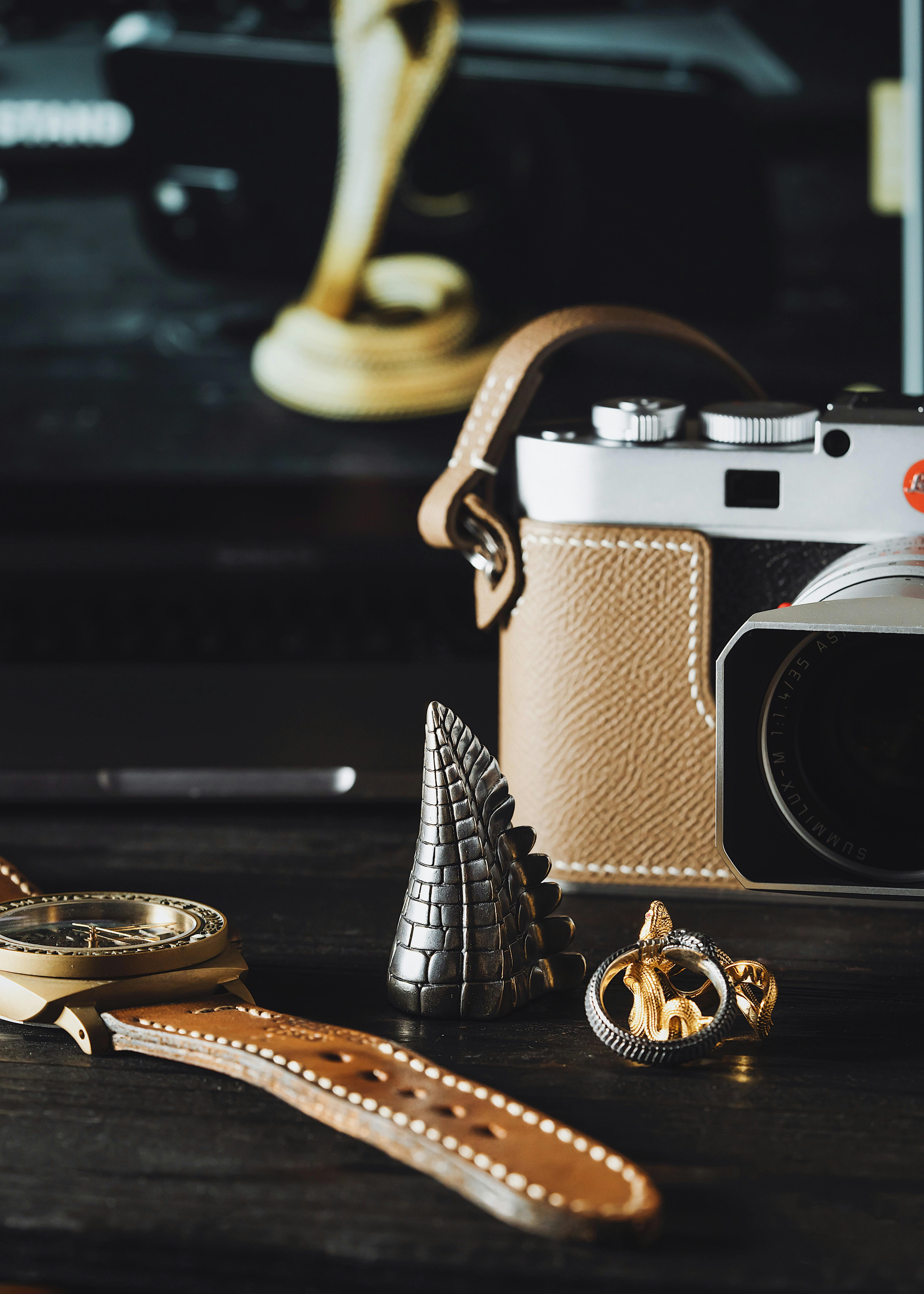 Elegant flat lay of a camera, watch, and decorative accessories on a wooden surface.