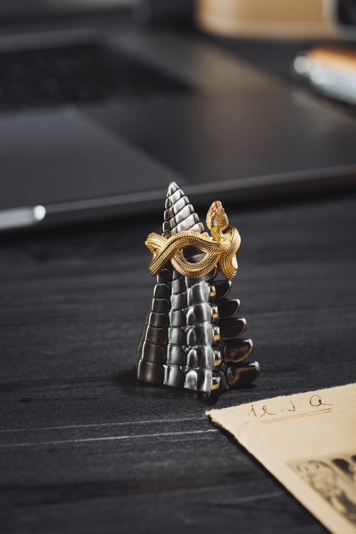 Free Close-up of a gold snake ring wrapped around a cone, set against a sophisticated dark tabletop. Stock Photo