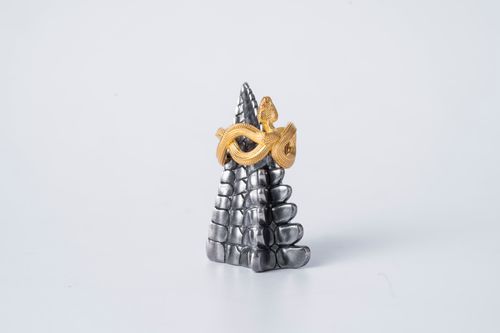 Free Close-up of a golden snake-shaped ring displayed on a metallic spike with a white background. Stock Photo