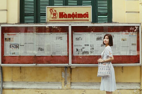 Woman in Dress Posing near Retro Advertising Board