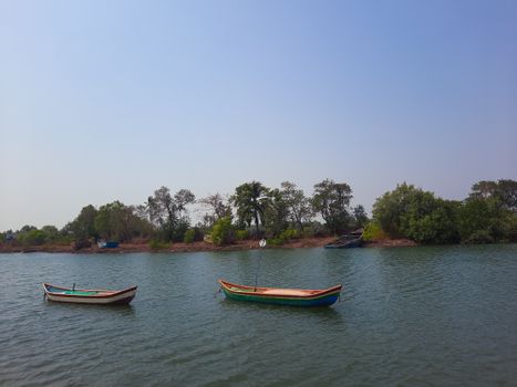 Peaceful landscape of river with two rowboats and lush greenery in India.