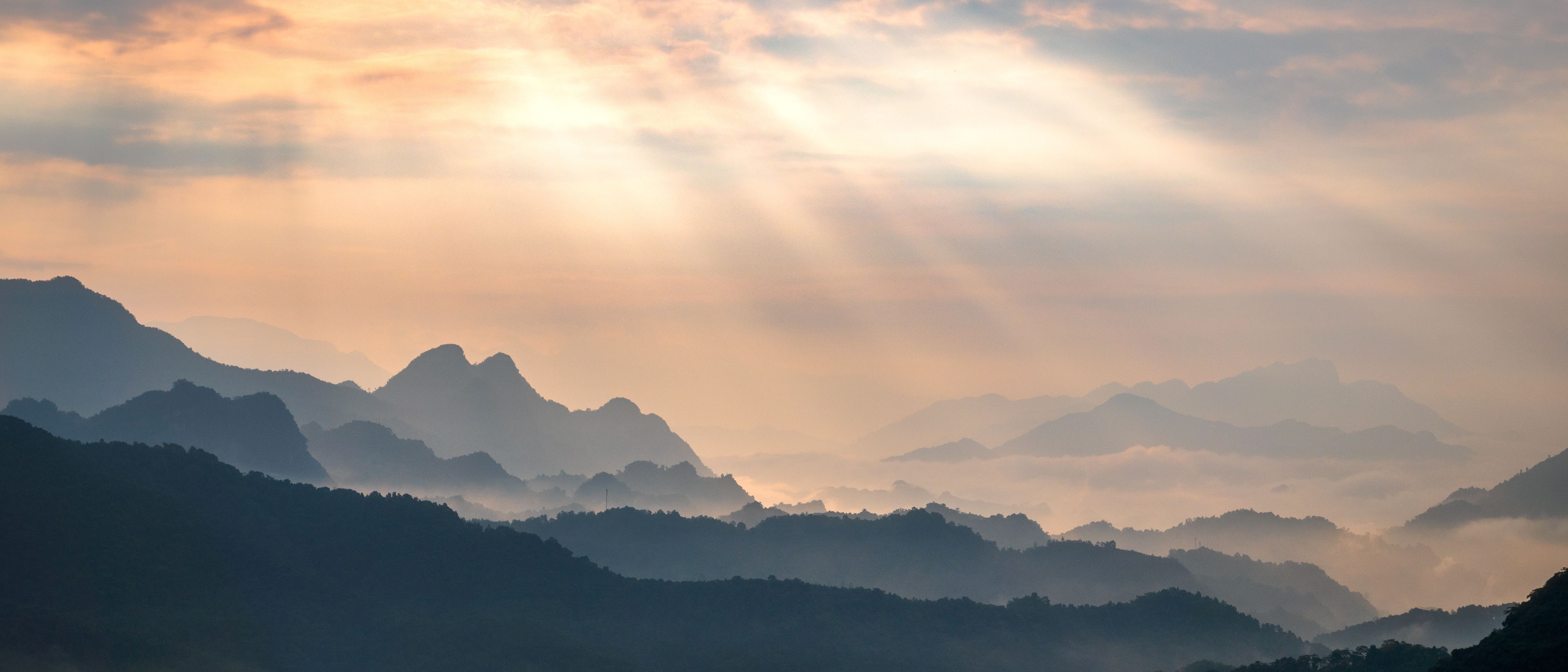[ColoSach]-peaceful-mountain-range-at-sunrise-with-sunlight-streaming-through-clouds.