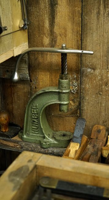 Fotomural Una herramienta de metal clásica en un taller vintage rodeado de paneles de madera y herramientas manuales.
