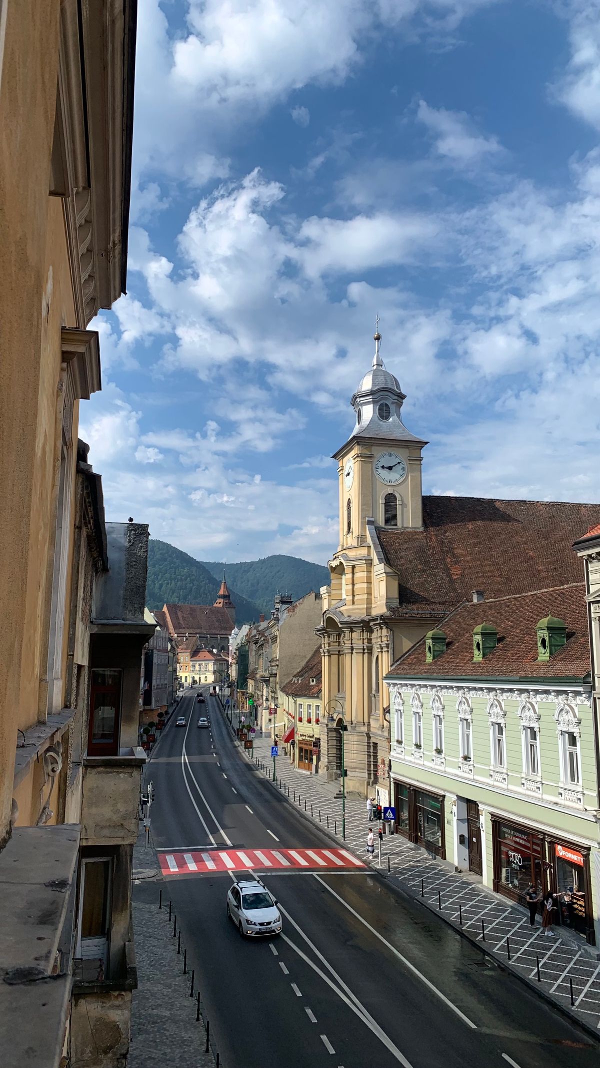 Centrul istoric Brașov - stradă cu case colorate și munții în fundal