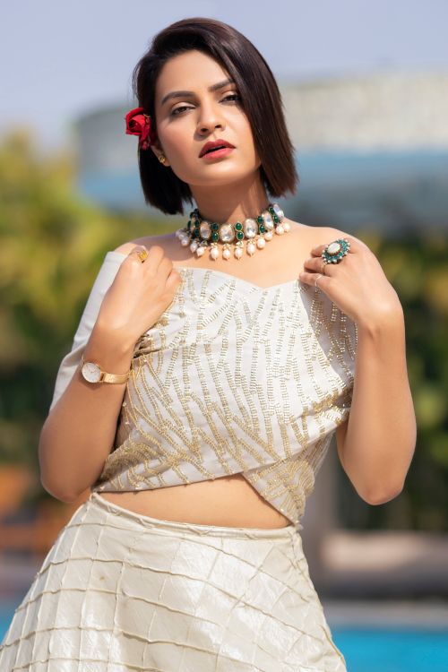Free Stylish woman posing with a white outfit and necklace, outdoors in bright light. Stock Photo