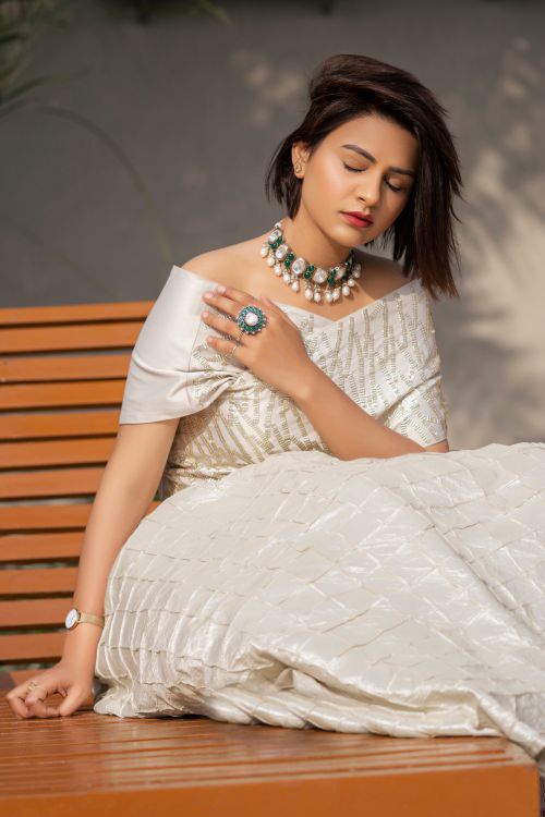 Free Fashionable woman in white dress sitting on a bench with elegant jewelry. Stock Photo