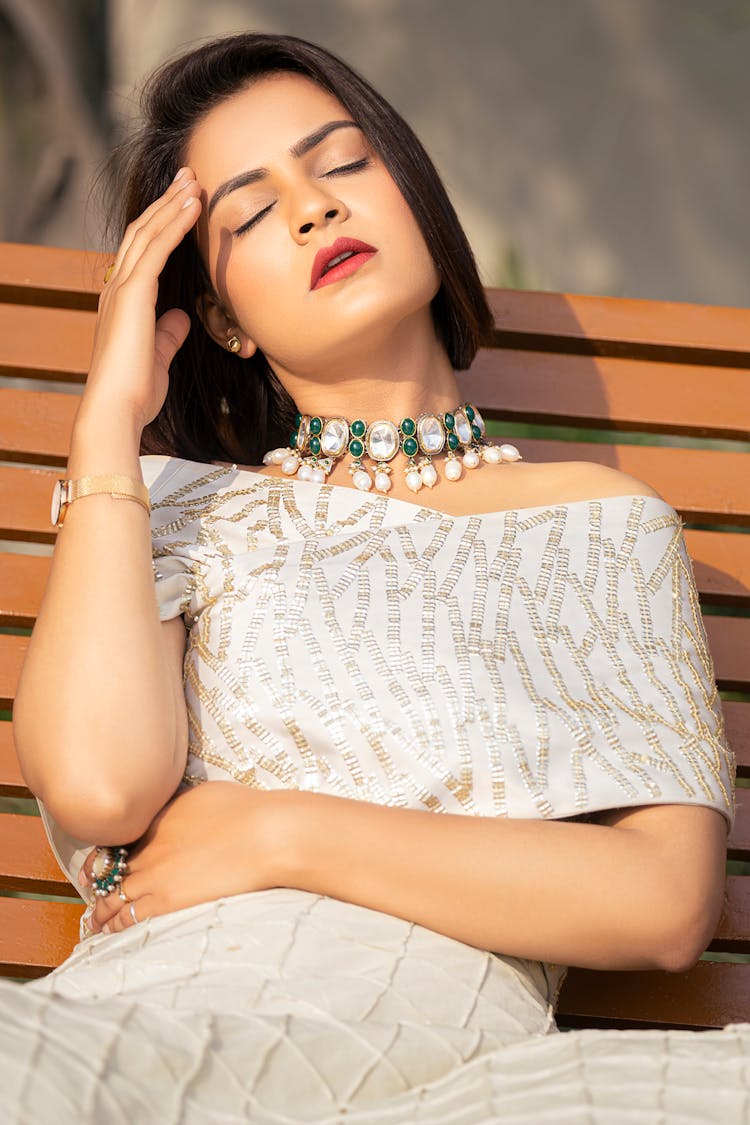 Tired Woman Sitting On The Bench And Touching Her Head 