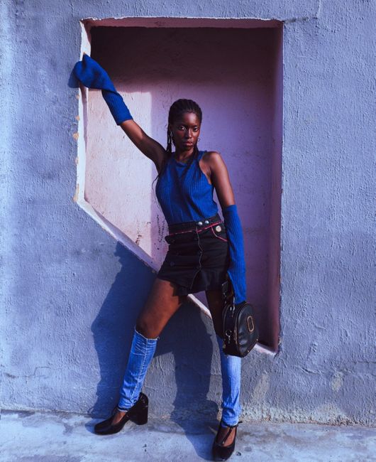 Fashionable woman in Lagos, Nigeria posing with a blue outfit and handbag.